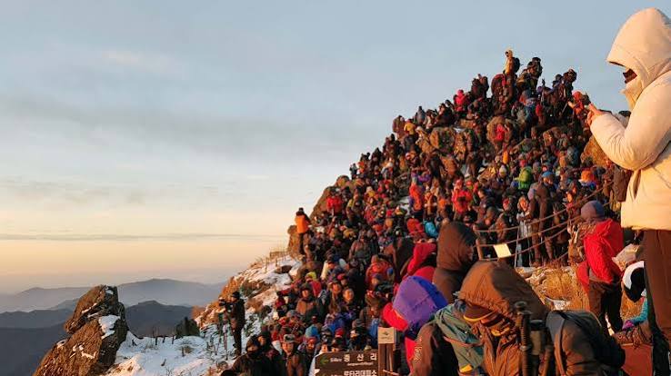 Visitors gathered on a snowy Seoraksan summit as the first sunrise light reaches the ridge