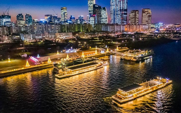 Illuminated Han River cruise boats travelling beside Seoul's night skyline