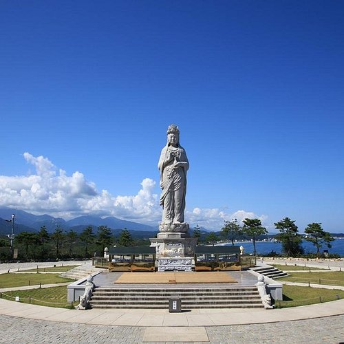 Large stone Buddhist statue facing the blue East Sea with Gangwon mountains in the distance