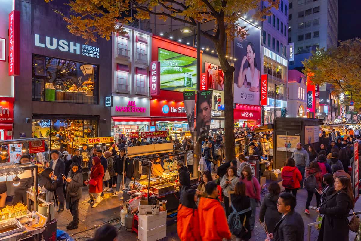 Bright Myeongdong shopping street at night with beauty store signs in Seoul