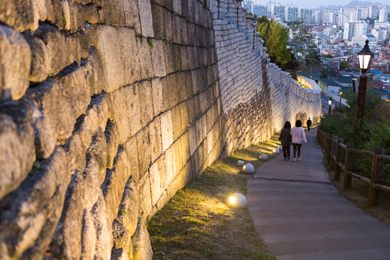 Illuminated Seoul City Wall path descending toward the city after sunset