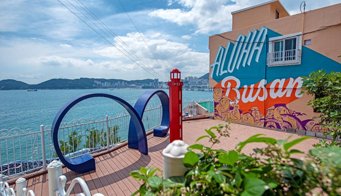 Colourful Huinnyeoul Culture Village terrace with a lighthouse sculpture and ocean view
