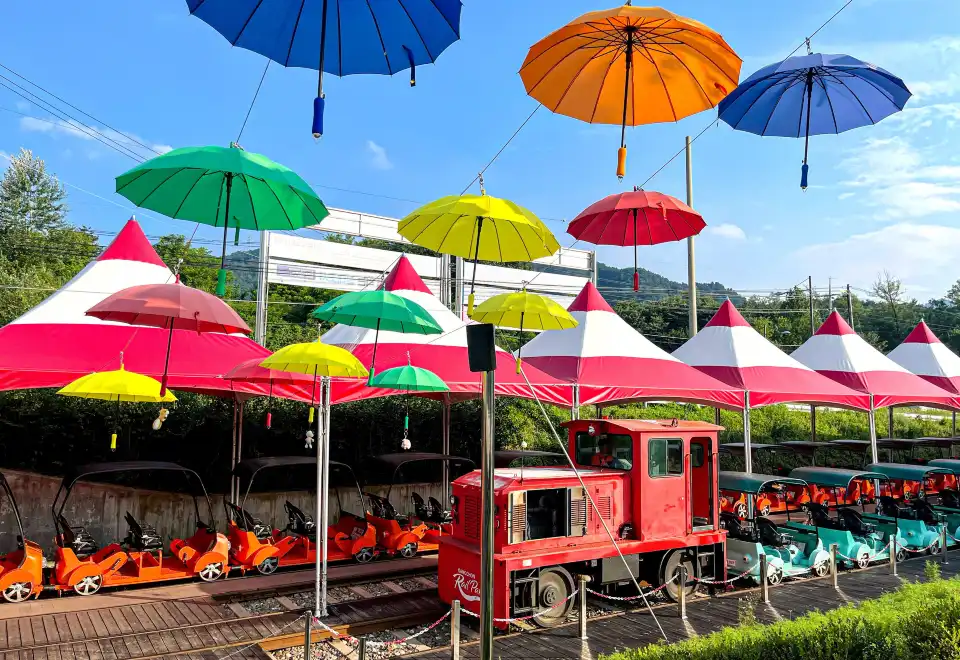 Colourful Gimyujeong rail bikes and parasols under a bright blue sky in Gyeonggi-do