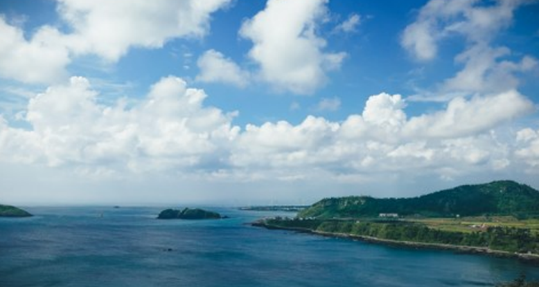 Bright clouds over the turquoise Jeju west coast with green headlands and small islets