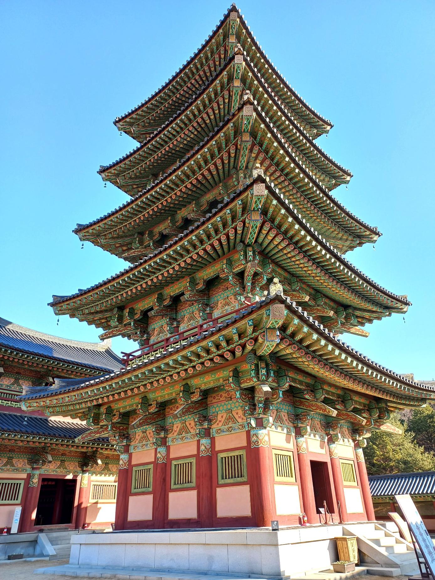 Brightly painted five-storey wooden pagoda at Baekje Cultural Land against a clear blue sky