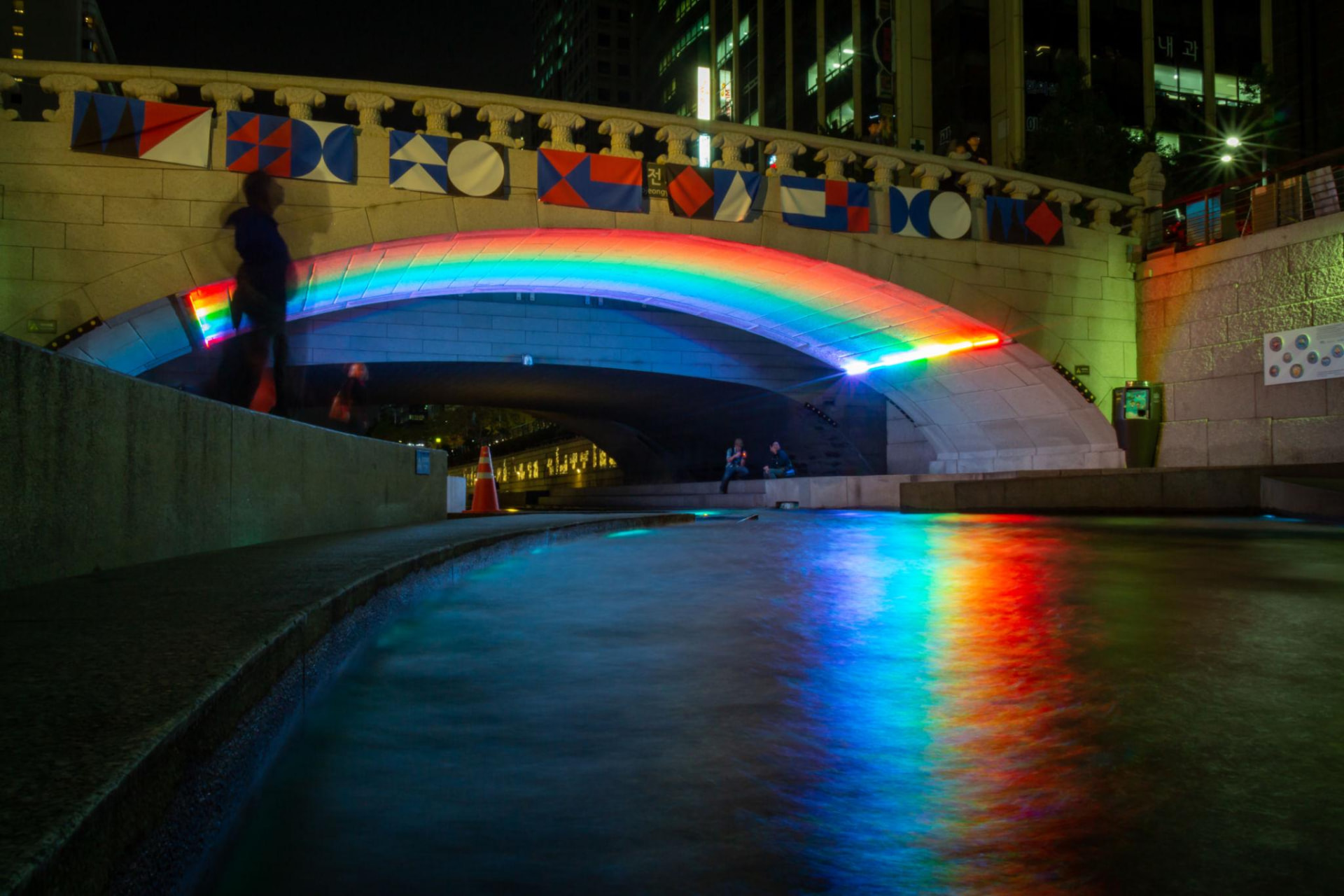 Rainbow lights reflected beneath a bridge over Cheonggyecheon stream at night