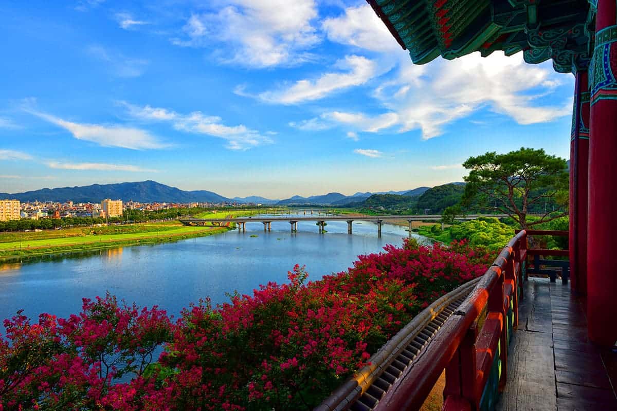 View across a Gyeongju river from a traditional pavilion framed by flowering trees
