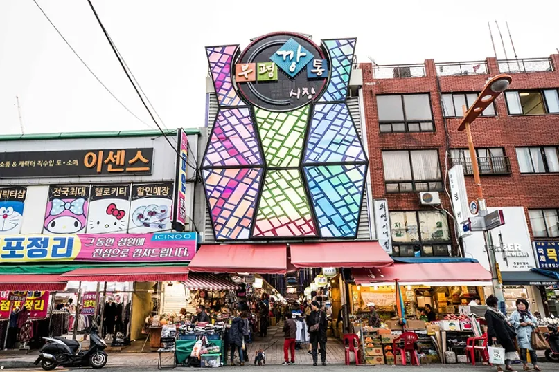 Entrance to Bupyeong Kkangtong Market with shops and visitors in Busan