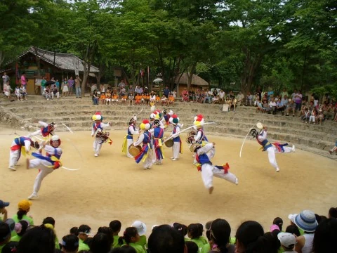 Traditional performers dancing in a circular outdoor arena watched by visitors