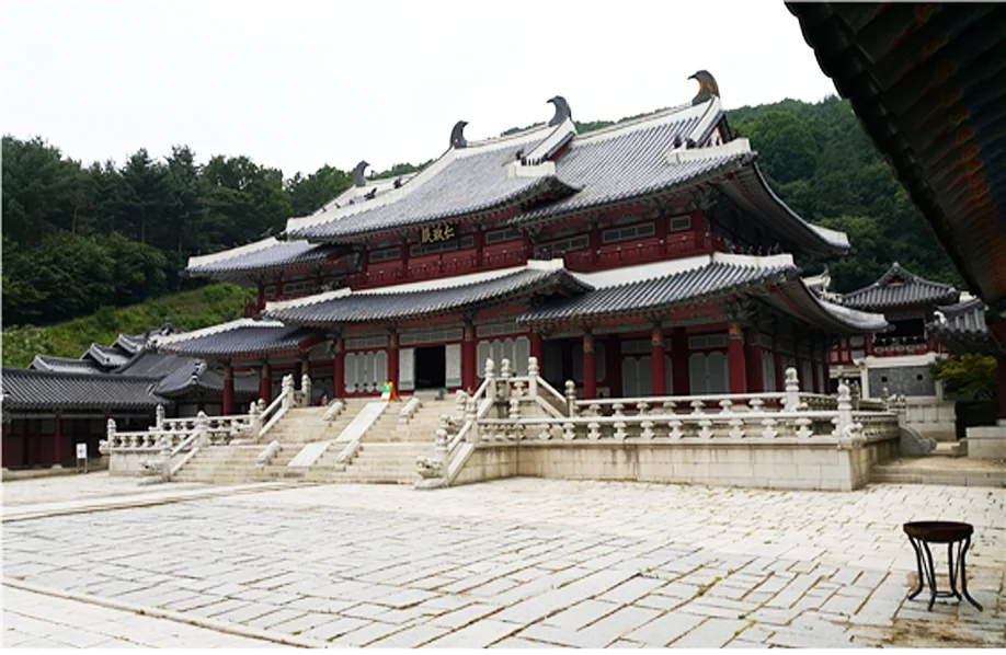 Grand red-pillared royal hall on a stone terrace with a paved courtyard at MBC Dae Jang Geum Park