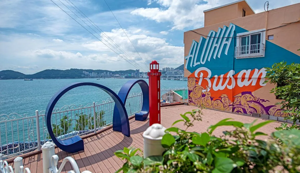 Colourful Huinnyeoul Culture Village terrace with a lighthouse sculpture and ocean view