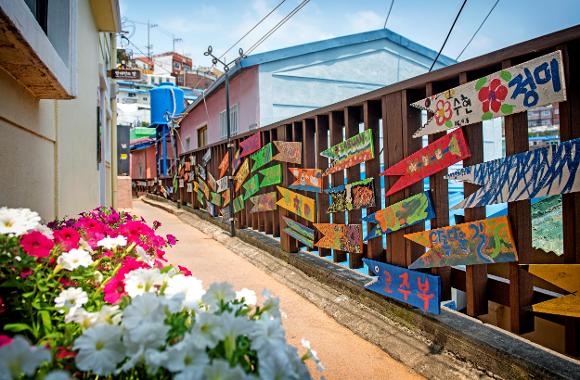 Colourful painted fish signs and flowers in a narrow lane of Gamcheon Culture Village