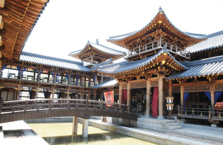 Multi-storey palace pavilion set linked by a wooden bridge over a pond at MBC Dae Jang Geum Park in Yongin