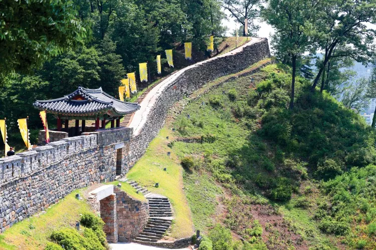 Stone rampart, steps and a traditional pavilion along the wooded wall of Gongsanseong Fortress