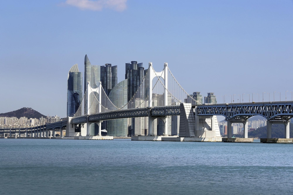 Gwangan Bridge seen from the water with Busan's skyline rising behind it on a clear day