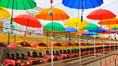 Red railbikes parked beneath a canopy of colourful umbrellas at Kim You-jeong Station