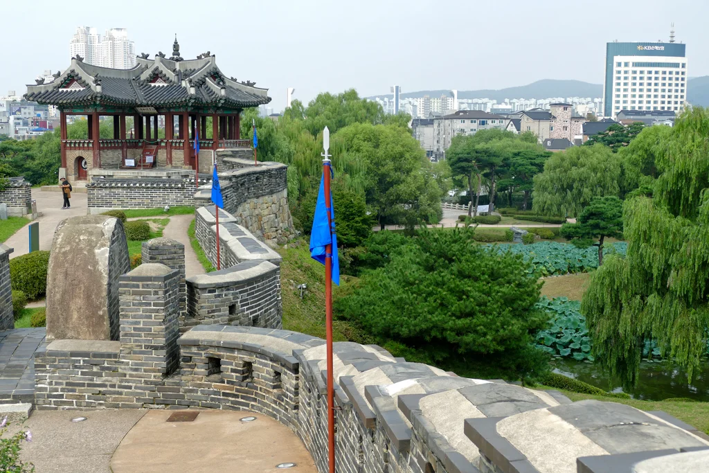 Curved Hwaseong Fortress wall and Dongbuk pavilion above a lotus pond