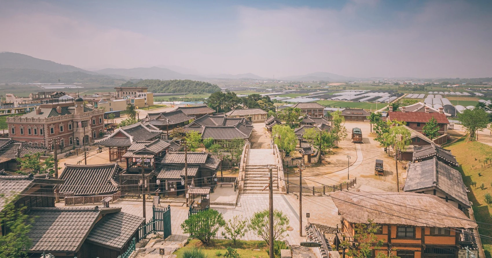 Panoramic view of Sunshine Studio in Nonsan with Glory Hotel, tiled-roof houses and a recreated period street