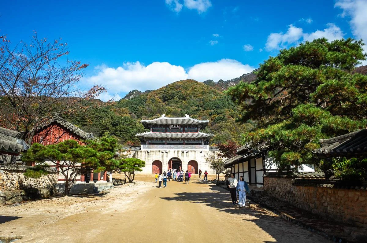 White palace-style gateway at the end of a broad courtyard lined with tiled-roof buildings in Mungyeong