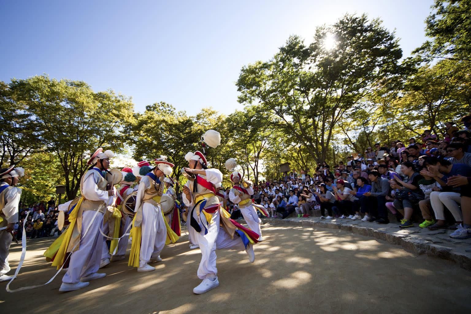 Farmer's music performers in white hanbok and ribbon hats dancing before a crowd