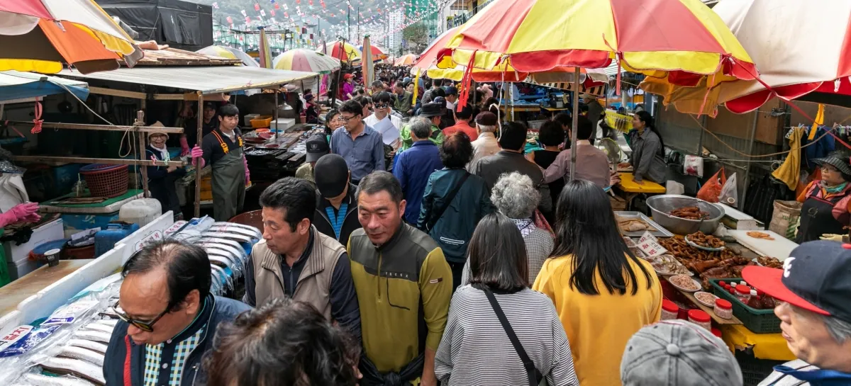 Busy seafood stalls beneath colourful umbrellas at Jagalchi Market in Busan
