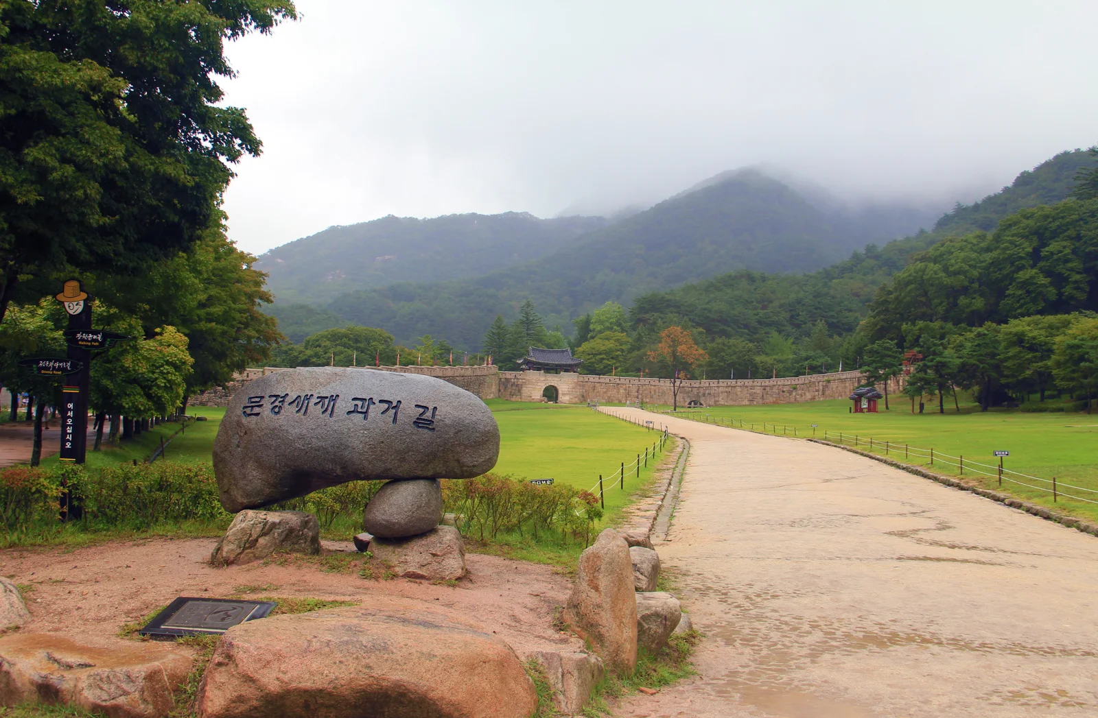 Juheulgwan, the first gate at Mungyeong Saejae, with wooded mountains behind the stone wall
