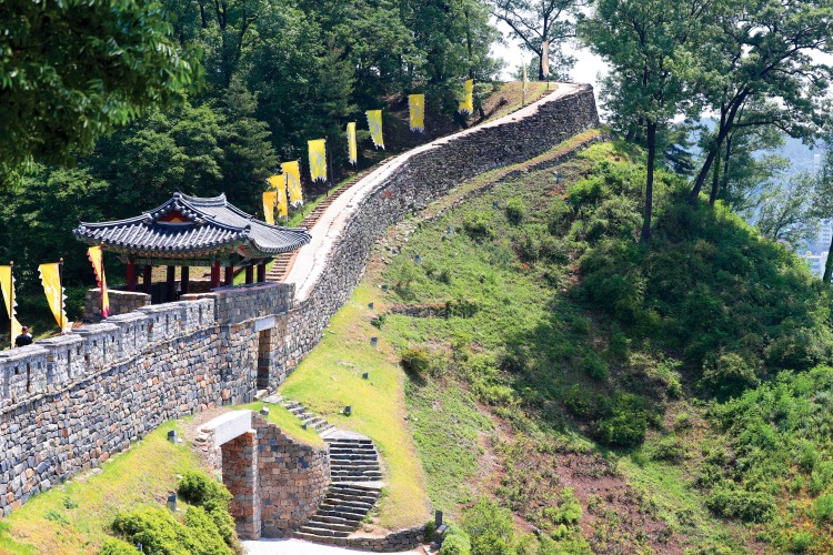Stone rampart, steps and a traditional pavilion along the wooded wall of Gongsanseong Fortress