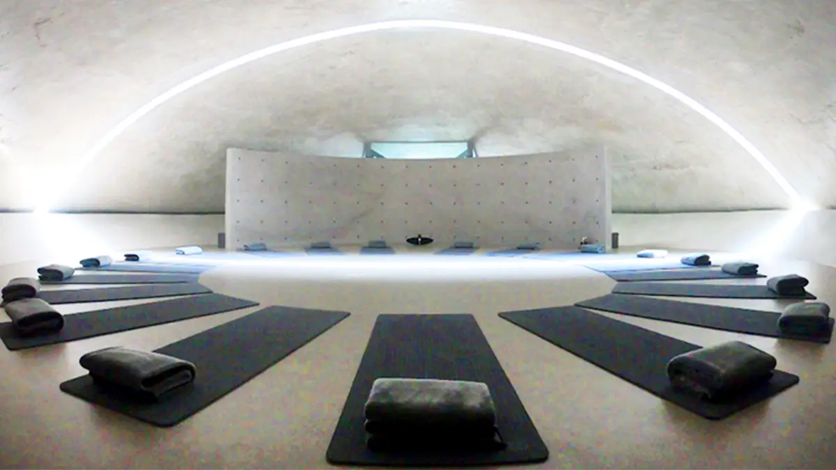 Minimal curved concrete meditation hall with cushions arranged in a circle at Museum SAN