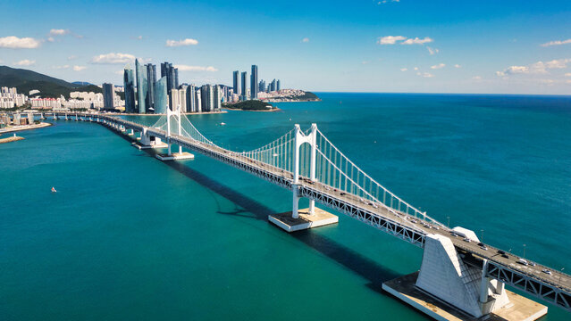 Aerial view of Gwangan Bridge spanning the blue sea with the Gwangalli skyline behind it