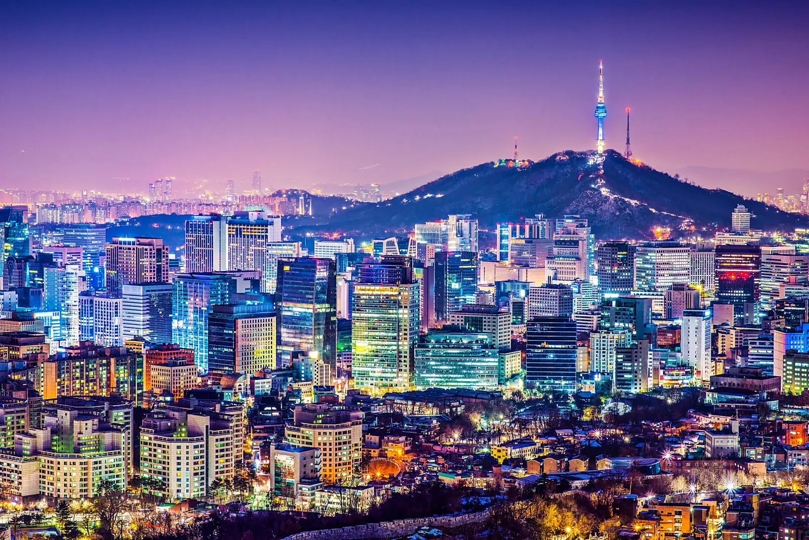Night view across Seoul's lit city blocks with N Seoul Tower glowing on the ridge of Namsan