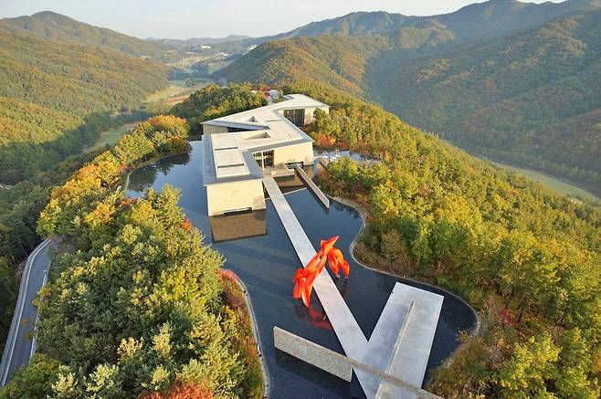 Aerial view of Museum SAN's geometric buildings and water gardens among forested mountains in Wonju