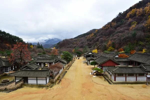Wide dirt road between traditional Korean buildings with forested mountains behind Mungyeongsaejae Open Set