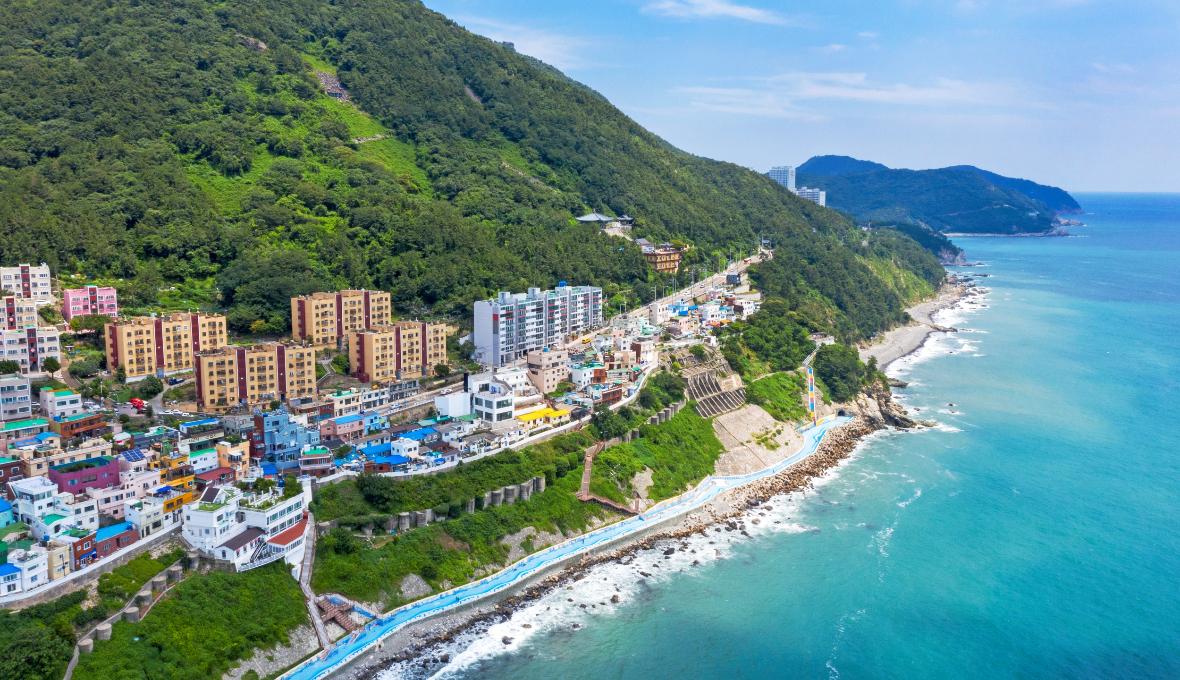 Aerial panorama of Huinnyeoul Culture Village and the blue beach trail along Busan's rugged coastline