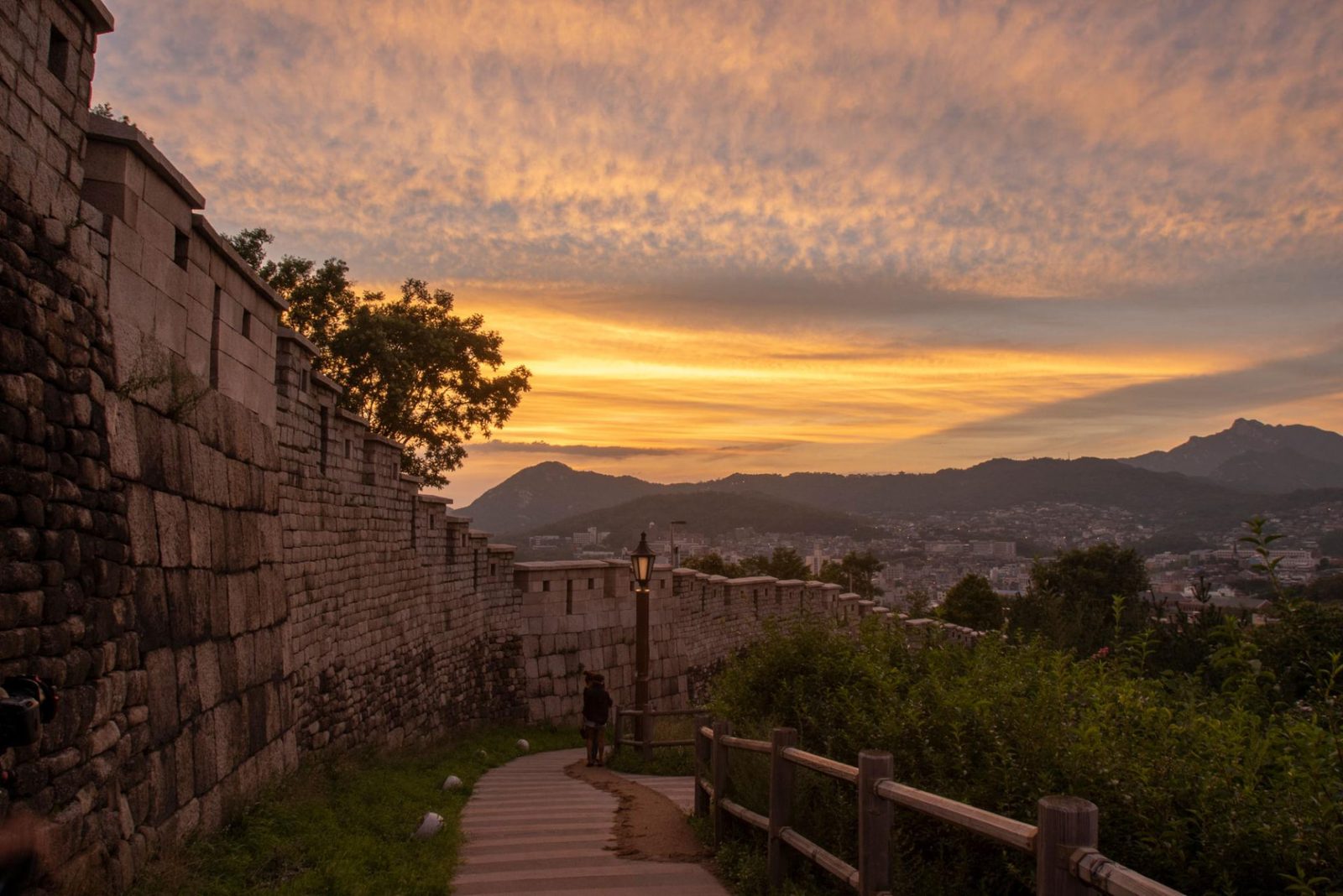 Pink and orange sunset clouds above the Seoul City Wall stone rampart and its walking path