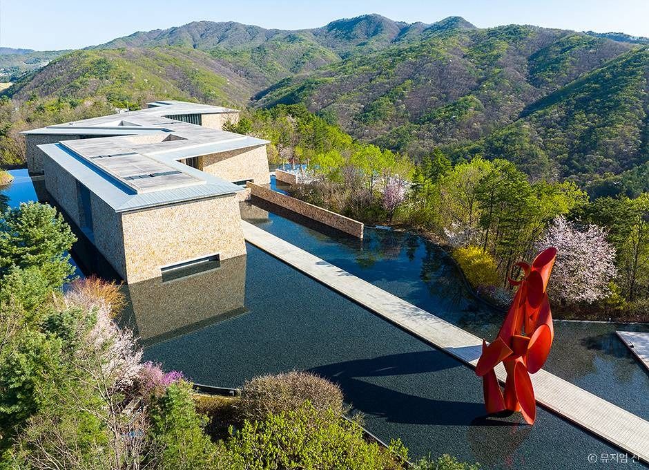 Museum SAN stone buildings, reflecting pool and red sculpture framed by green mountains