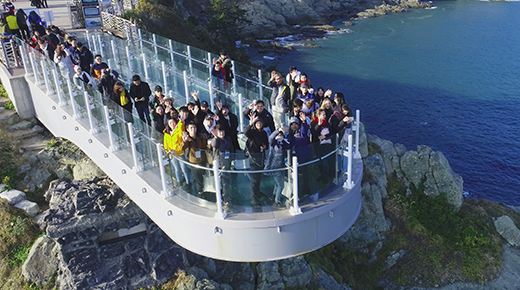 Visitors standing on the glass-floored Oryukdo Skywalk above the sea