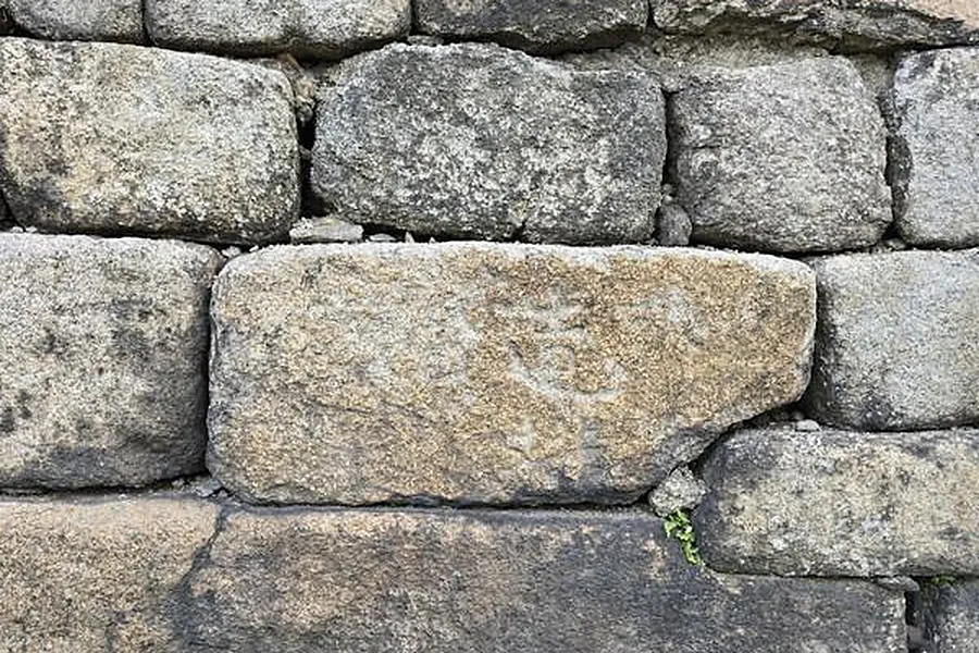 Close-up of a Seoul City Wall stone block bearing a carved construction mark made by the crew that built the section