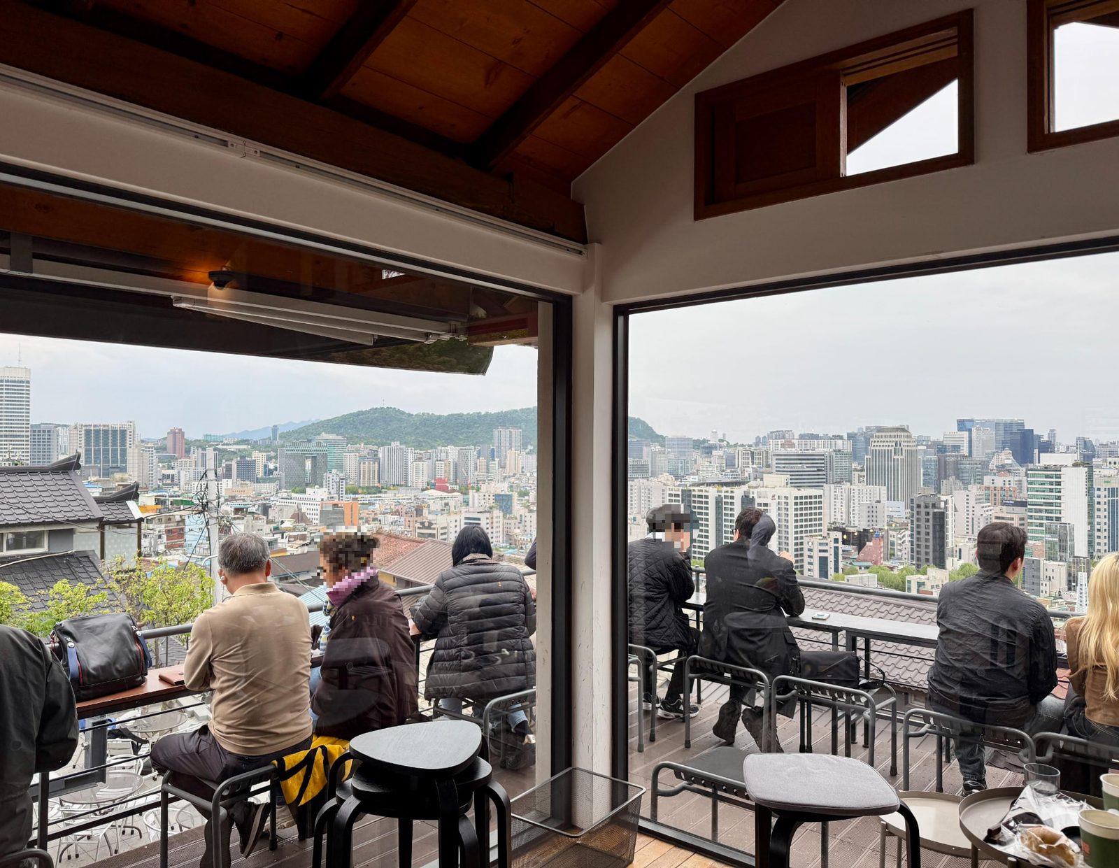 Guests seated at a hillside café terrace in the Ihwa-dong area overlooking the Seoul skyline
