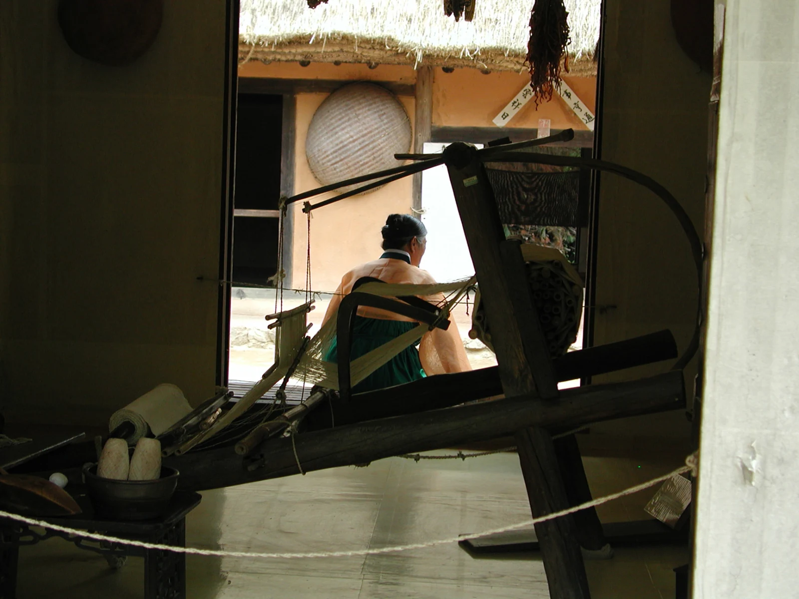 Wooden weaving loom inside a traditional building with a visitor beyond the doorway