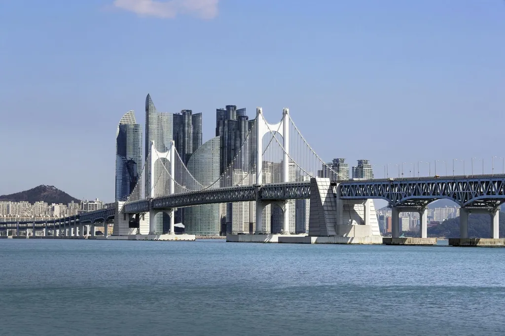 Gwangan Bridge seen from the water with Busan's skyline rising behind it on a clear day