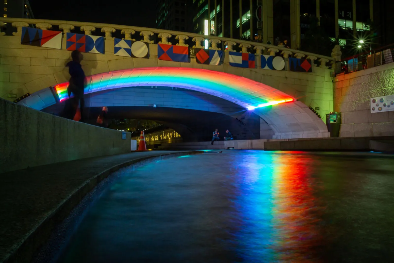 Rainbow lights reflected beneath a bridge over Cheonggyecheon stream at night