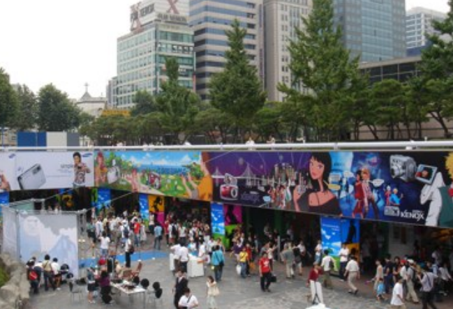 Colourful K-pop culture displays and visitors in an outdoor plaza in Gangnam, Seoul