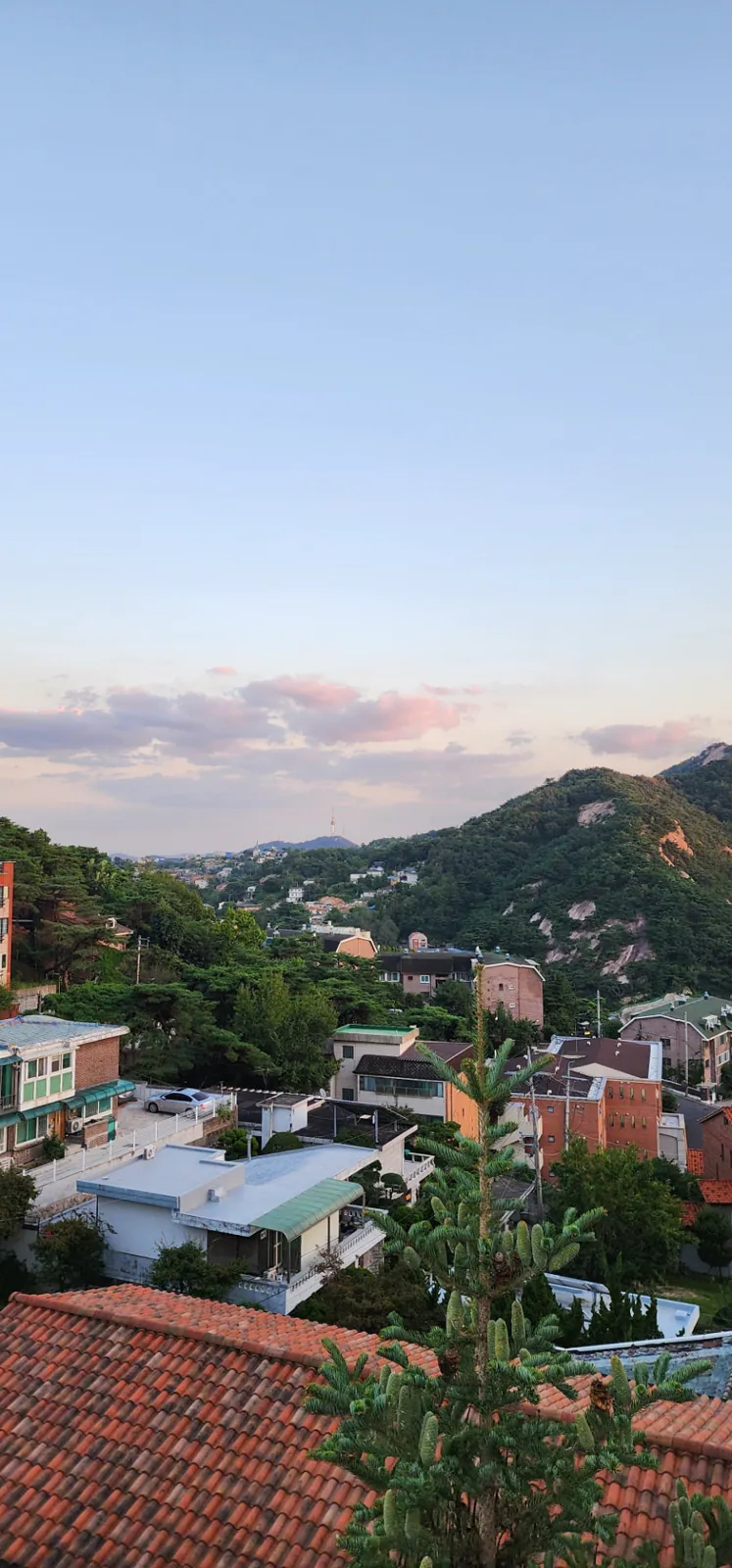 Bukchon rooftops and Inwangsan Mountain beneath a soft evening sky