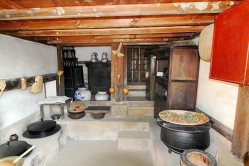 Traditional kitchen with iron cauldrons, earthenware jars and wooden cabinets