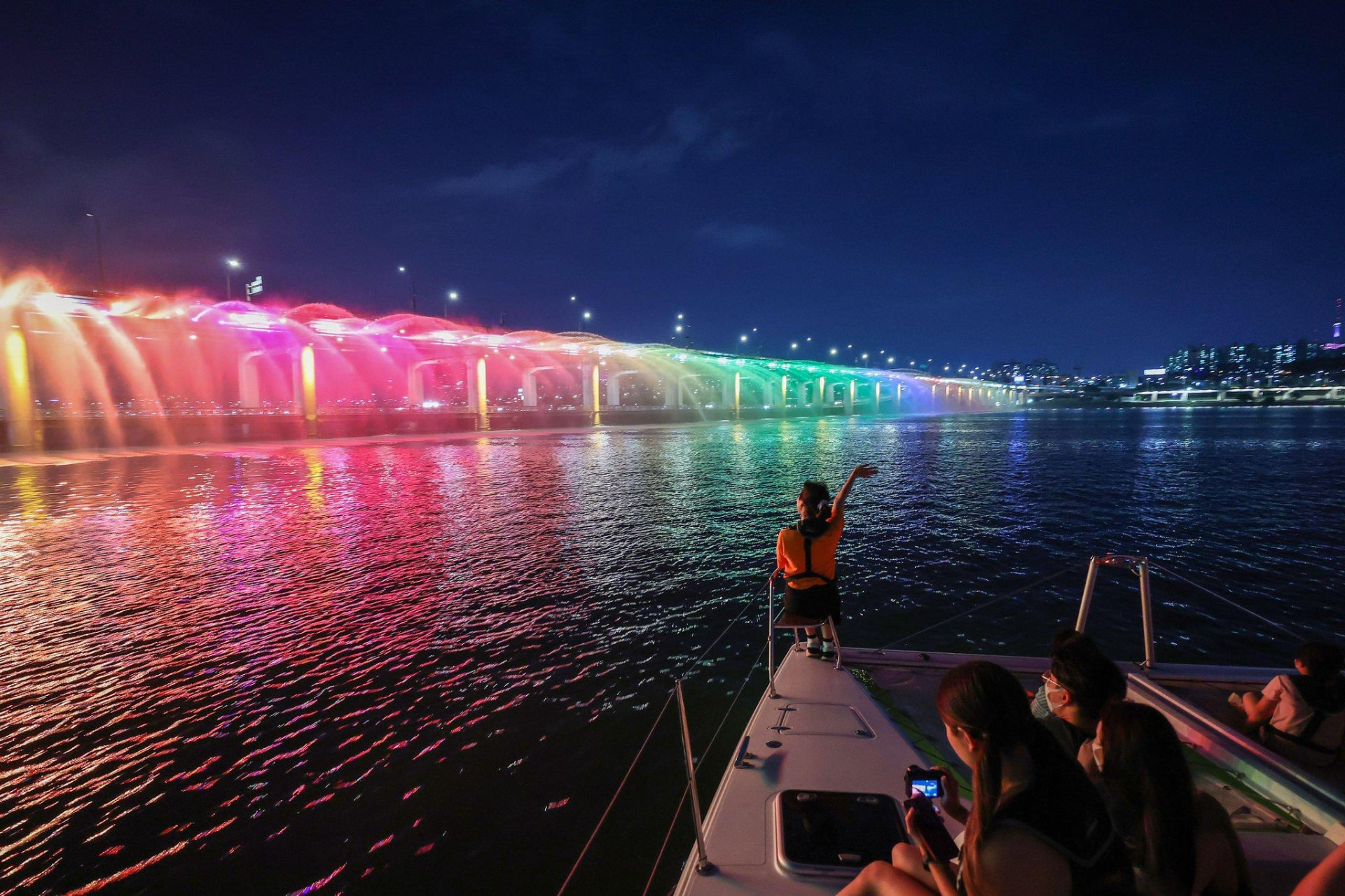 Passengers viewing the colourful Banpo Rainbow Fountain from a Han River cruise at night
