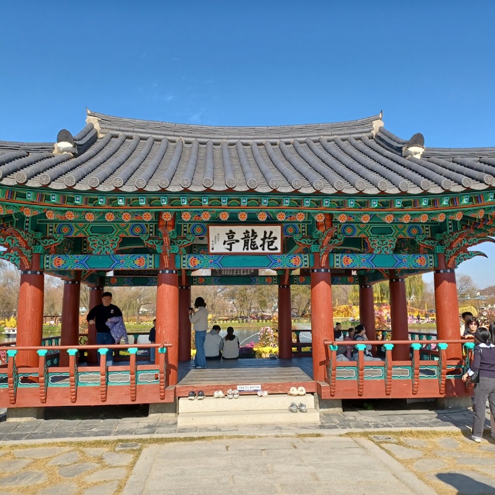 Colourfully painted Poryongjeong pavilion at Gungnamji pond with visitors sitting inside
